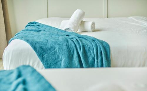 a white bed with a blue blanket on it at Empire Damansara Petaling Jaya by COBNB in Petaling Jaya