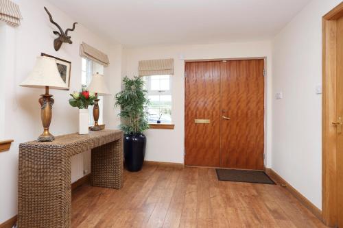 a hallway with a wooden door and a table at JOIVY Greenknowes Farmhouse with Hot Tub and Bar in Kelty