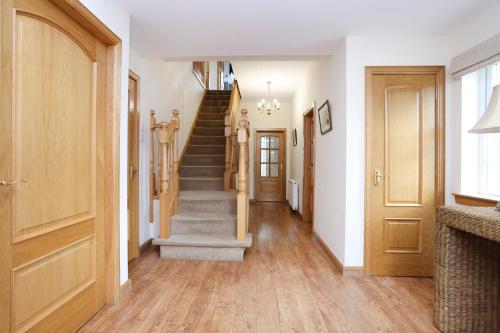 a hallway with stairs in a home with wooden floors at JOIVY Greenknowes Farmhouse with Hot Tub and Bar in Kelty