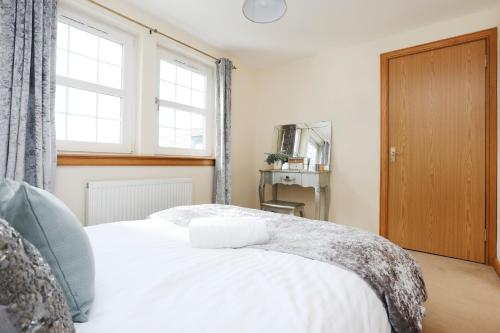 a bedroom with a white bed and a window at JOIVY Greenknowes Farmhouse with Hot Tub and Bar in Kelty