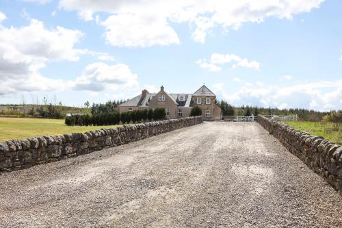 a dirt road in front of a house with a stone wall at JOIVY Greenknowes Farmhouse with Hot Tub and Bar in Kelty