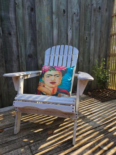 a wooden rocking chair with a pillow on a deck at Forest Waters Raspberry Dream Cabin in Haruru