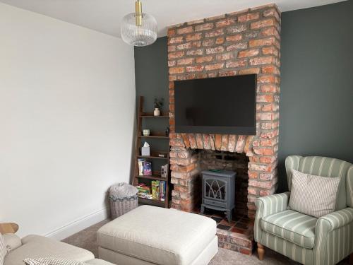 a living room with a brick fireplace with a television at The Cottage - Cosy Filey Home in Filey