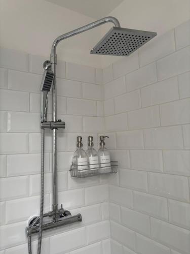 a bathroom with a shower with three bottles of soap at The Cottage - Cosy Filey Home in Filey