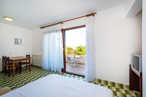 a bedroom with a bed and a table and a window at Bady Apartments with BBQ in Novalja