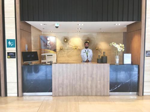 a man standing behind a counter in a lobby at Megaworld Furnished Studio Near Mall/Marriott/ICC in Iloilo City