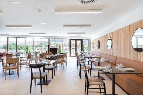 ein Esszimmer mit Tischen, Stühlen und Fenstern in der Unterkunft Parador de Molina de Aragón in Molina de Aragón