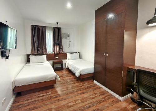 a hotel room with two beds and a tv at Ambien's Place Residential Hotel in Dagupan