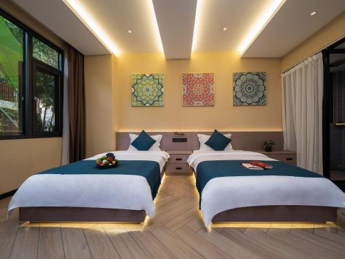 two beds in a room with yellow walls and windows at Yun Guan Shunde Renjia Resort Hotel in Jinghong