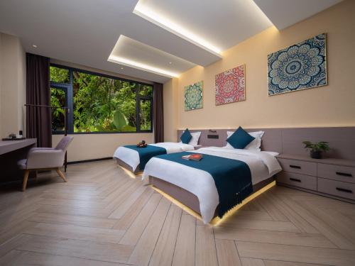 a bedroom with two beds and a desk and a window at Yun Guan Shunde Renjia Resort Hotel in Jinghong