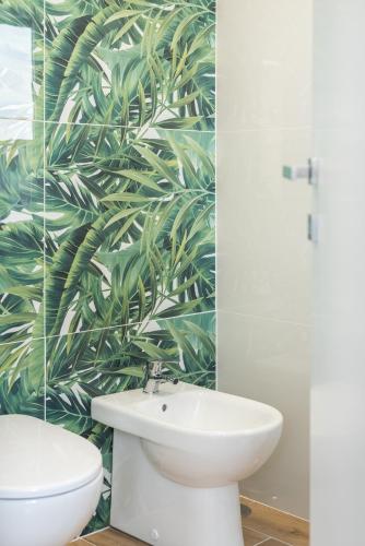 a bathroom with a white sink and a green leaf wallpaper at MM Ciampino Rooms in Ciampino