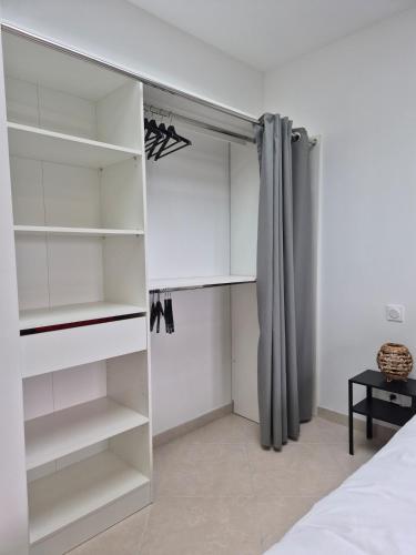 a closet with white shelves and a curtain at Appartement 80m2 entre vignes et Mont Ventoux in Vaison-la-Romaine