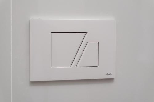 a light on a white wall with a mirror at MM Ciampino Rooms in Ciampino