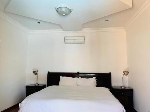 a bedroom with a bed with white sheets and a ceiling at Leruo's Guest House in Kimberley