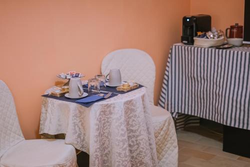 a table with two white chairs and a table with food on it at Palazzo Romani Adami in Fermo
