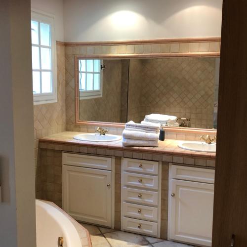 une salle de bain avec deux lavabos et un grand miroir dans l'établissement La maison à couleur - Mas provençal avec piscine, à Châteaurenard