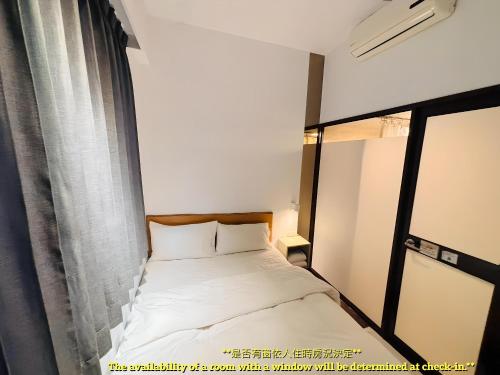 a small bed in a room with a window at Lütel Hotel Xpark Gloria Outlets Shin Kong Cinemas in Dayuan