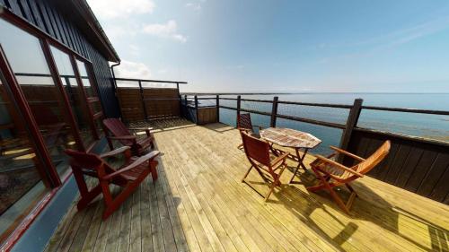 a balcony with chairs and a table and the ocean at Kleifar: Ocean View Apartment in Hellissandur