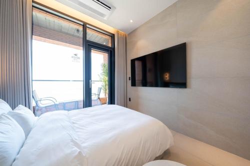 a bedroom with a white bed and a tv at Hound Hotel Deacheon Beach in Boryeong