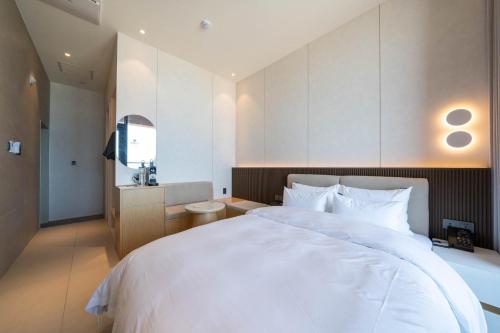 a bedroom with a large white bed and a television at Hound Hotel Deacheon Beach in Boryeong