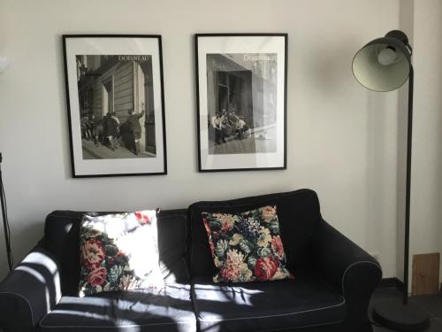 a black leather couch in a living room with three pictures at Côté campagne in Pierrefaites