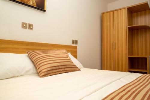 a bedroom with a white bed with a wooden headboard at Hôtel ZUMAH in Ouagadougou