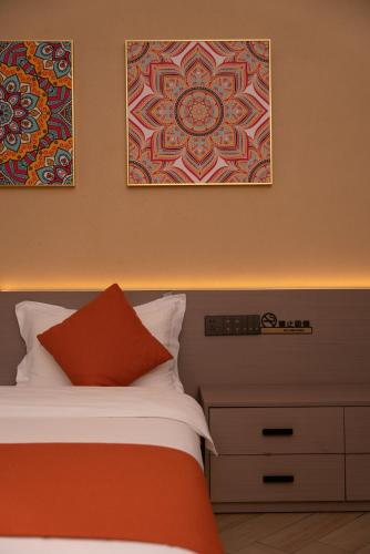 a bedroom with a bed and two pictures on the wall at Yun Guan Shunde Renjia Resort Hotel in Jinghong