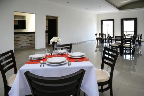 ein Esszimmer mit einem Tisch und einem weißen Tischtuch in der Unterkunft Hotel Victoria Inn in San Juan del Río