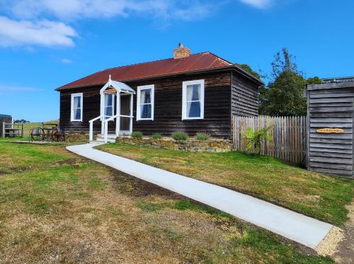 a small brown house with a red roof at Ruby's Cottage Farm Stay in Port Arthur
