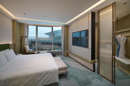 a hotel room with a bed and a tv at Holiday Inn Wuhan Tianhe Airport by IHG in Wuhan