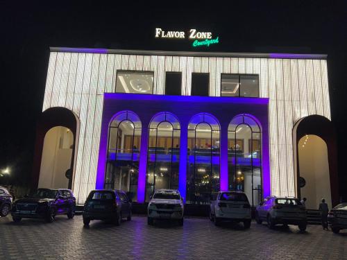 Un edificio con coches aparcados delante por la noche. en Flavour Zone Courtyard, en Ambāla