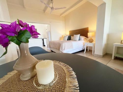 a room with a table with a vase with purple flowers at Beachbreak Cottages in Durban