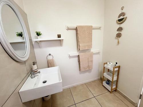 a bathroom with a sink and a mirror and towels at Beachbreak Cottages in Durban