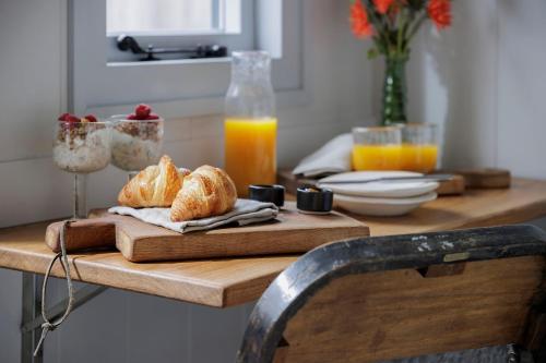 a table with croissants on a cutting board with orange juice at Luxury Shepherd hut with hot tub in Alcester