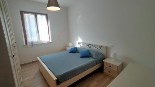 a bedroom with a bed with blue pillows and a window at Villetta a schiera trilocale cod 492 - Taunus vacanze in Numana