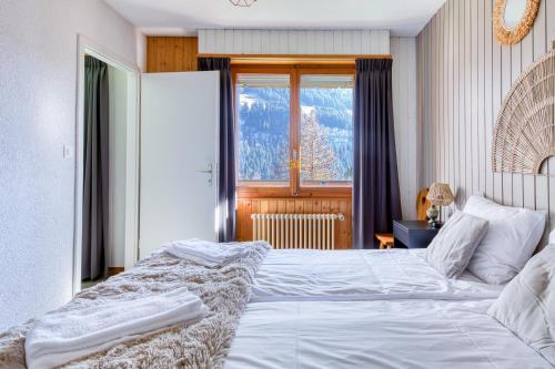 a bedroom with a large white bed and a window at Val Air F75, Peace & Panoramic Views in Champéry
