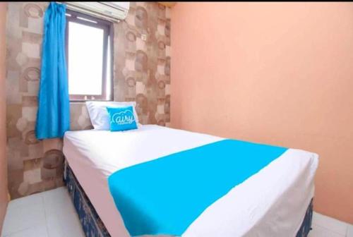 a bedroom with a bed with blue curtains and a window at Ambon Residence Syariah in Ambon