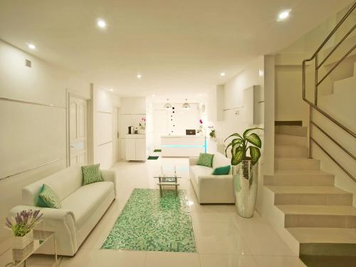 a living room with two white couches and a staircase at Planktons Beach in Hulhumale