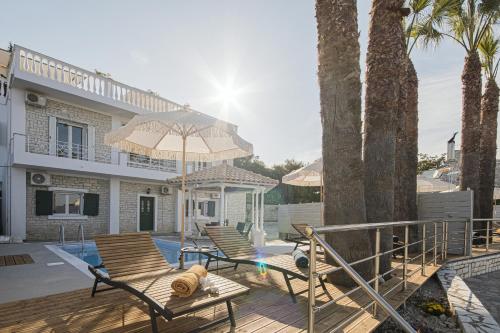 a house with a deck with chairs and an umbrella at La Vista Residence - 5 BDS, 2 private swimming pools, stunning sea views only 10 minutes from Corfu Town's Centre in Gouvia