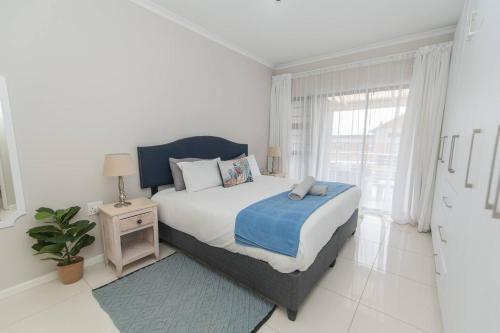 een witte slaapkamer met een bed en een raam bij The Sapphire in Gqeberha