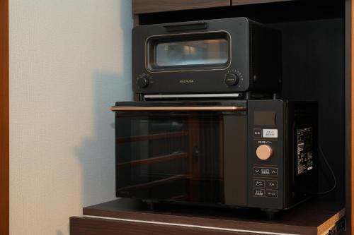 a microwave and a television on top of a toaster oven at パーパスリゾート EG Sky terrace 熱川 in Higashiizu