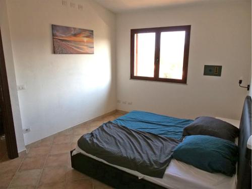 a bed in a room with a window at Appartamento Estate in Limpiddu