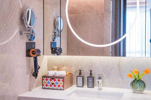 a bathroom with a sink and a mirror at Yuexiu Hotel Guangzhou,Curio Collection by Hilton-Free shuttle between hotel and Exhibition Center during Canton Fair & Exhibitor Registration Counter in Guangzhou