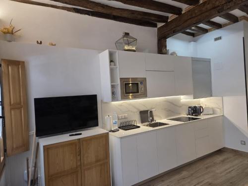a kitchen with white cabinets and a flat screen tv at El Patio de Vespasiano- San Juan- vistas al ayuntamiento junto al puerto in Castro-Urdiales