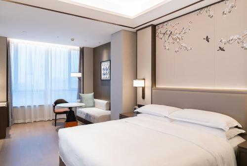 a hotel room with a bed and a chair at Yuexiu Hotel Guangzhou,Curio Collection by Hilton-Free shuttle between hotel and Exhibition Center during Canton Fair & Exhibitor Registration Counter in Guangzhou
