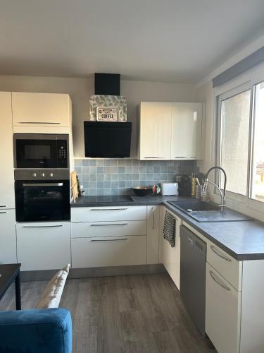 une cuisine avec des placards blancs et un mur en carrelage bleu dans l'établissement Le Citadin T3, à Marseille