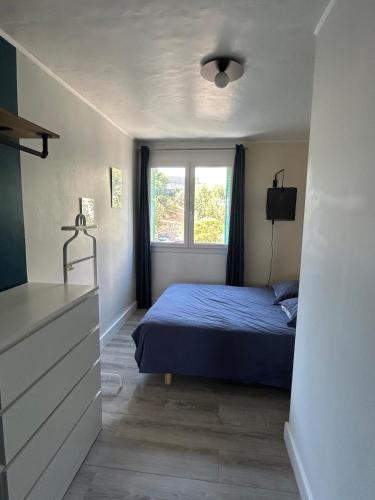une chambre avec un lit bleu et une fenêtre dans l'établissement Le Citadin T3, à Marseille