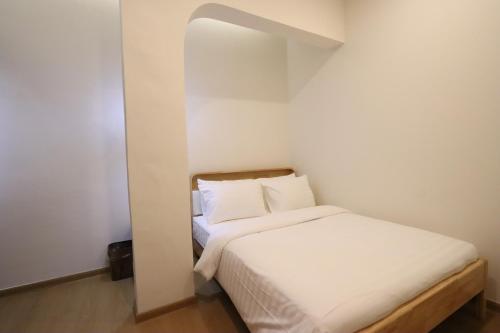 a small bedroom with a bed with white sheets at Casabella Homestay 202 Batam Penuin in Nagoya