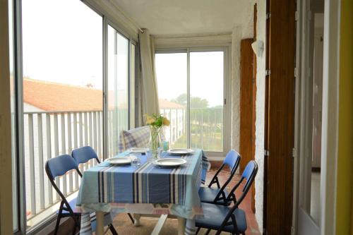 une table à manger avec des chaises bleues et une fenêtre dans l'établissement Appartement 2 pièces 5 couchages ARGELES SUR MER AR350-0D3, à Argelès-sur-Mer