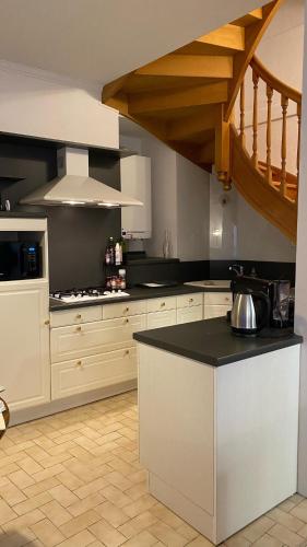 une cuisine avec des armoires blanches et un comptoir noir dans l'établissement Maison-Cœur historique-Sarlat, à Sarlat-la-Canéda